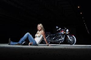 sexy blonde zit in de buurt van haar motorfiets