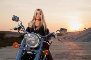 sexy blonde zittend op haar motorfiets foto