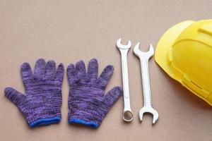 handschoenen, sleutels en geel moeilijk hoed voor monteur en bouw werk. concept, klusjesman, monteur hulpmiddelen. steeksleutels. uitrusting voor vaststelling of repareren, vernieuwing in dagelijks leven. foto