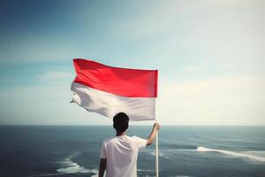 een Mens Holding een rood en wit Indonesië vlag op zoek Bij de oceaan. ai gegenereerd foto