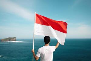 een Mens Holding een rood en wit Indonesië vlag op zoek Bij de oceaan. ai gegenereerd foto