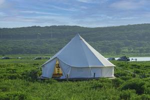 witte tent in een veld met bewolkte blauwe hemel foto