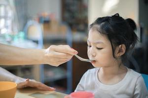 een klein meisje eet iets van een lepel. foto