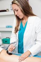 dokter het uitvoeren van een ultracavitatie behandeling Aan een jong vrouw geduldig been foto