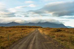 onverharde weg over een herfst gekleurd veld in IJsland foto