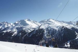 toeristen in ski liften met sneeuw bergen in achtergrond foto