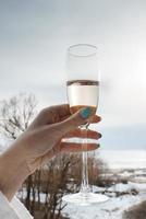 vrouw hand- Holding Champagne fluit in voorkant van natuur Bij hotel foto