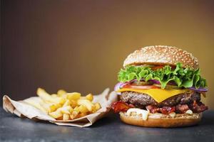 grote cheeseburger met hoop frietjes op leisteen bord foto