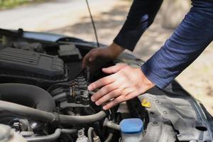 een Mens Aan de kant van de weg is vaststelling een auto. handen Aan de kap. auto reparatie Aan de weg. machine afbreken. foto