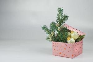 roze doos met gouden Kerstmis ballen en groen takken van Kerstmis boom foto
