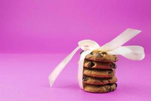 vijf koekjes met chocola druppels en wit lint Aan roze achtergrond foto