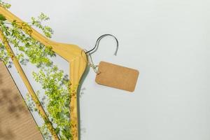 houten hanger met groen takken en leeg etiket Aan blauw achtergrond foto