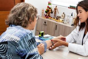 traumatoloog vrouw dokter Bij haar kantoor onderzoeken een senior vrouw geduldig. skelet bot ziekte tentamen en medisch hulp. carrière concept. foto