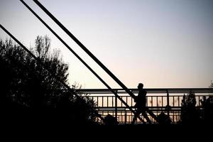 lopende man uitzicht tegen de hemel. menselijk silhouet op de brug. foto