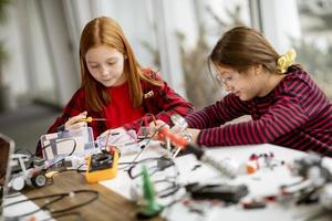 schattige kleine meisjes die elektrisch speelgoed en robots programmeren in het klaslokaal voor robotica