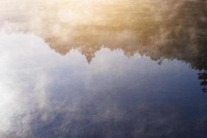 mooi landschap hemel van de nevel en mist over- de meer en zonsopkomst schijnend met blauw lucht reflectie Aan de water oppervlakte Bij heuvel stam dorp Aan berg in Thailand foto