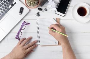 bedrijf hand- Mens schrijven Aan blanco notitieboekje Aan tafel, foto