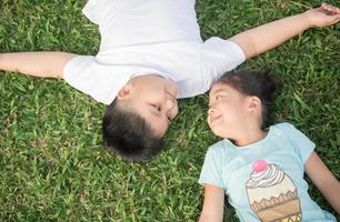 glimlach kinderen liggen naar beneden Aan gras foto