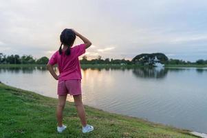 terug kant van weinig meisje oefening Aan park met zonsondergang foto