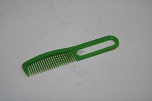 foto van een groen haar- kam gemaakt van plastic met een wit achtergrond