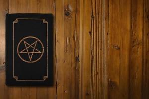 satanisch boek Aan een houten bureau foto