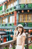 vrouw reiziger bezoekende in Taiwan, toerist met hoed bezienswaardigheden bekijken in jiufen oud straat dorp met thee huis achtergrond. mijlpaal en populair attracties in de buurt Taipei stad . reizen en vakantie concept foto