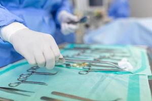 in werking kamer van chirurgisch tafel met instrumenten, assistent picks omhoog instrumenten voor chirurgen gedurende operatie. chirurgie in voortgang. professioneel medisch artsen het uitvoeren van chirurgie. foto