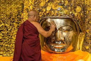 mandala, Myanmar - jul 17, 2018-senior monnik wassen de gezicht van mahamuni Boeddha beeld Bij mahamuni tempel. de meest zeer vereerd Boeddha beeld in de land. foto