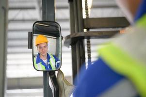 arbeider in auto onderdelen magazijn gebruik een heftruck naar werk naar brengen de doos van auto onderdelen in de opslagruimte plank van de magazijn aan het wachten voor levering naar de auto bijeenkomst lijn foto