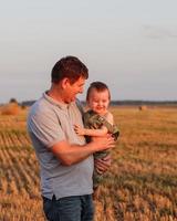 gelukkig vader en zoon hebben pret Aan de veld- Aan een heet zomer dag. concept van vriendelijk familie en van zomer vakantie foto