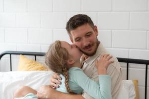 een weinig meisje drukt uit zijn gevoelens voor zijn vader. door omarmen net zo spoedig net zo u wakker worden omhoog in de begin van de dag foto