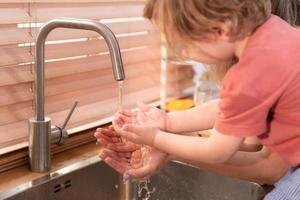 moeder en kind wassen uw handen grondig in de wastafel voordat binnengaan de keuken foto