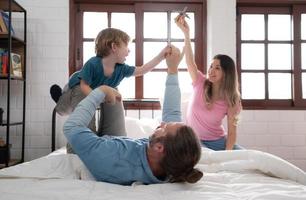 weinig jongen vliegend met vader gebruik makend van zijn poten naar helpen hem vlieg hoog uit de verdieping van zijn bed in de slaapkamer. foto