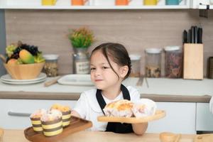 portret van een weinig meisje in de keuken van een huis hebben pret spelen bakken brood foto