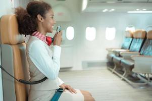 vlucht begeleider sprekend door een luidspreker naar Welkom passagiers en geven advies Aan op reis door vlak foto