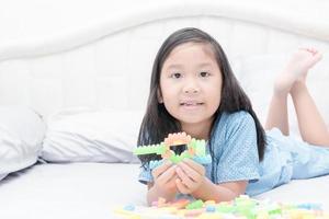 schattig Aziatisch meisje Speel blok bakstenen Aan bed foto