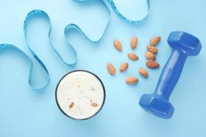 bovenaanzicht van een meetlint, halter, amandelnoten en melk op blauwe achtergrond foto