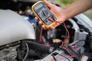 Aziatische automonteur check voor reparatie onder de motorkap van kapotte auto aan de kant van de weg. foto