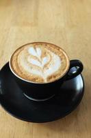 een kopje late koffie met bloemvormig ontwerp bovenop in café foto