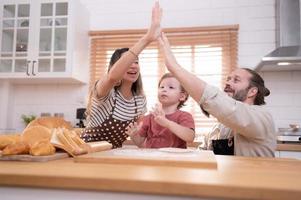 mam en vader in de keuken van de huis met hun klein kinderen. hebben een mooi zo tijd bakken brood en maken avondeten samen. foto