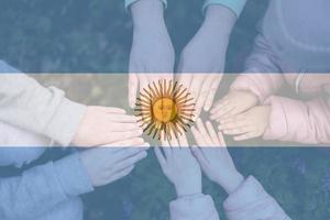 handen van kinderen Aan achtergrond van Argentinië vlag. Argentijns patriottisme en eenheid concept. foto