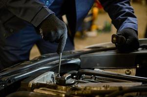 detailopname auto monteur handen met moersleutel repareren auto in de garage van een reparatie winkel foto