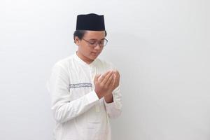 portret van jong millennial Aziatisch moslim Mens bidden ernstig met zijn handen verhoogd. geïsoleerd beeld Aan wit achtergrond foto