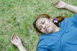 jong Aziatisch vrouw flauwvallen Aan gras in park omdat buitenshuis van heet weer foto