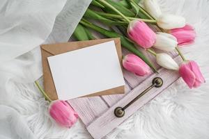 een boeket van tulpen en bespotten omhoog blanco wit papier kaart voor tekst. vlak leggen, top visie. plaats voor tekst. groet kaart foto