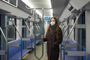 een vrouw met een medisch gezichtsmasker bewaart sociale afstand in een moderne metro foto