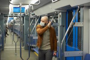 een man met een baard zet een medisch gezichtsmasker op in een metro foto