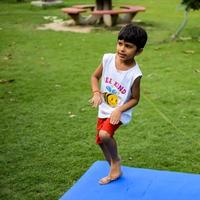 Aziatisch slim kind aan het doen yoga houding in de maatschappij park buitenshuis, kinderen yoga houding. de weinig jongen aan het doen yoga oefening. foto