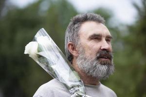 portret van een gebaard middelbare leeftijd Mens met een boeket van bloemen. foto