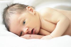 de gezicht van een pasgeboren baby met Open ogen en klein armen. foto